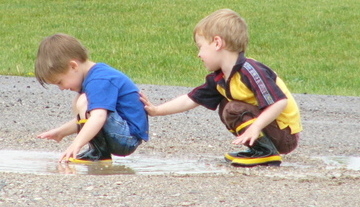 boy patting brother's back after putting mud in his pants