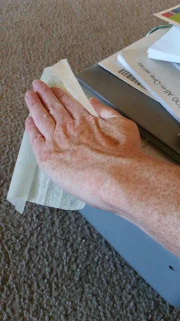 hand using Clorox dust wipe to clean printer