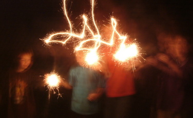 boys waving sparklers in dark