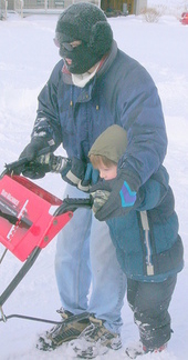 boy helping dad push snowblower