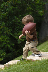 toddler boy walking holding football