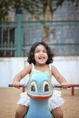 girl joyfully playing on playground toy