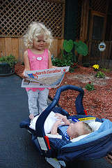 small girl reading map to baby