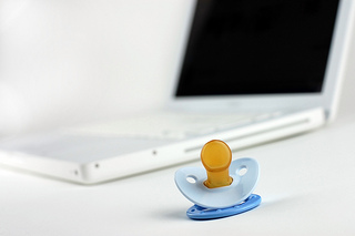pacifier lying in front of white laptop computer