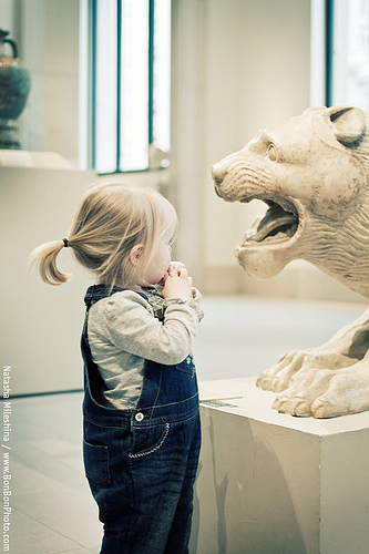 girl in museum looking at lion sculpture