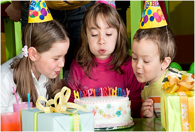 young kids blowing out candles on birthday cake