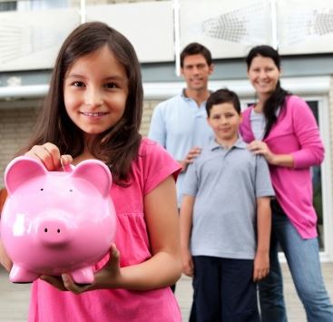 girl holding piggy bank, parents and brother standing behind