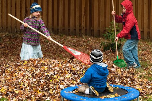 children raking leaves together