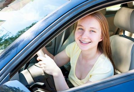 teen girl at wheel, smiling