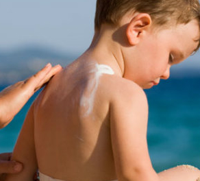 sunscreen being applied to a boy's back