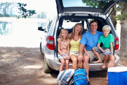 family sitting in back of car packed to travel