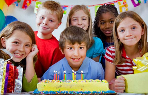 children smiling in front of birthday cake