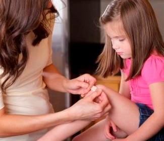mom putting bandaid on daughter's knee