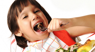 smiling child eating a bite of food