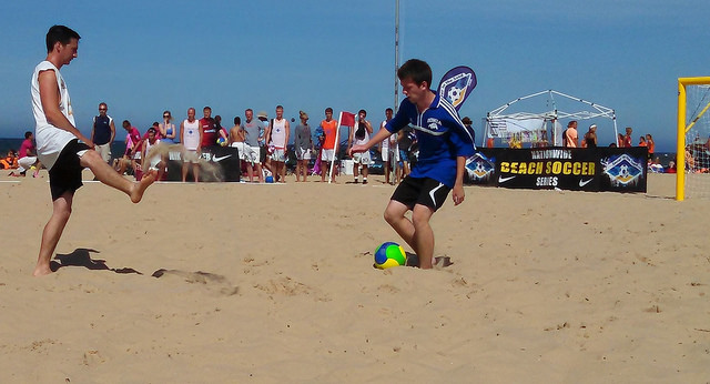 boy playing defensive soccer on the beach