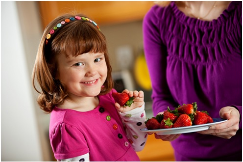girl smiling ready to eat a strawberry